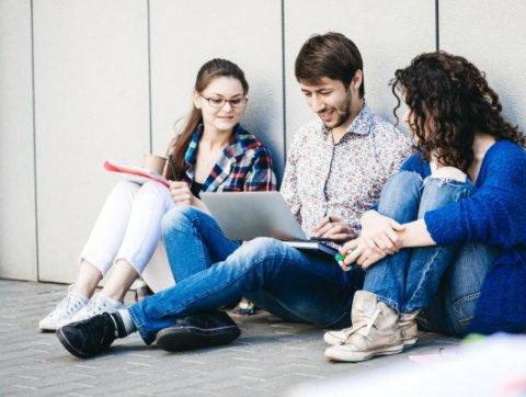 Young people are using different gadgets and smiling, sittin